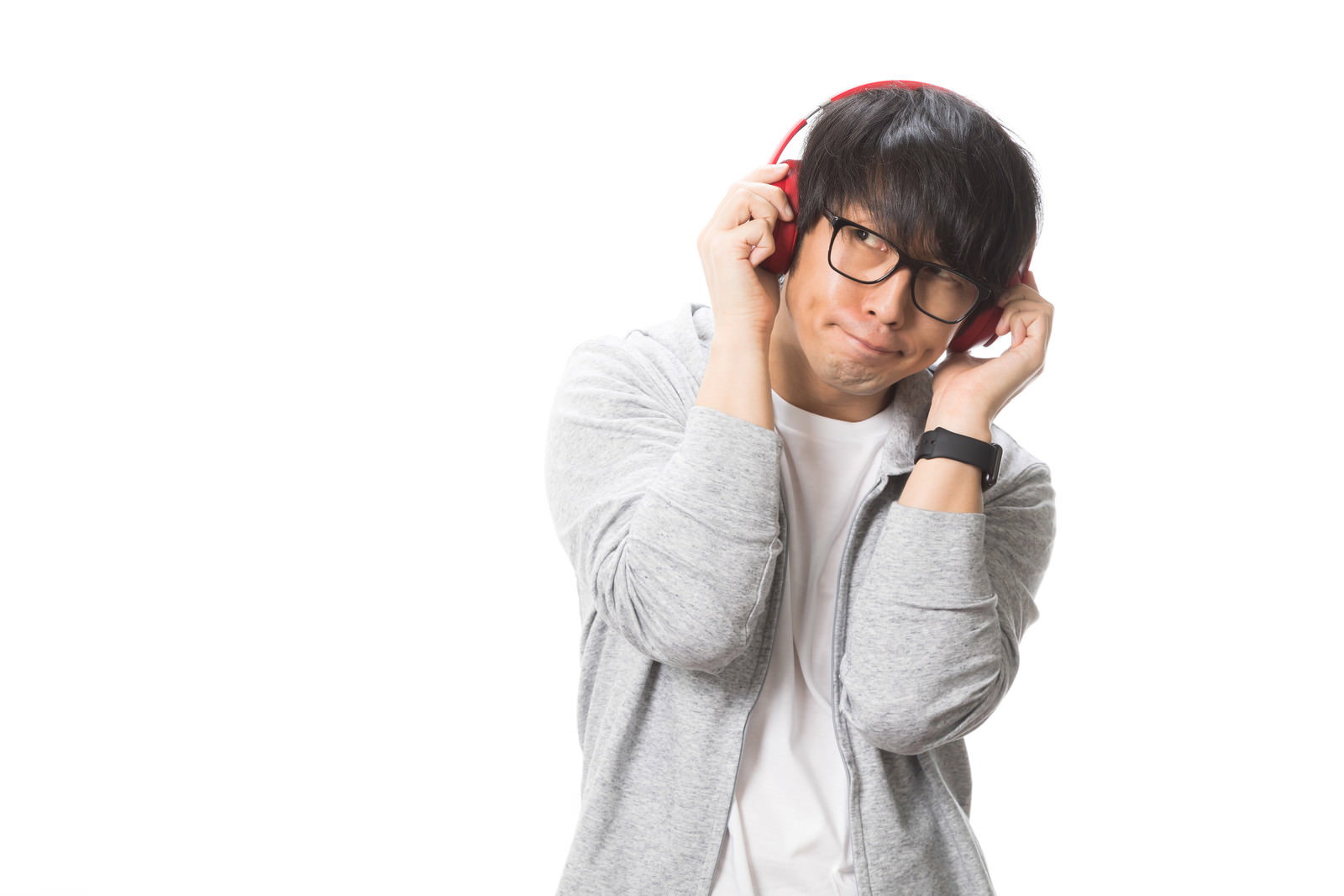 グレーのパーカーを着た男性が大型のヘッドフォンで音楽を聴いている様子［モデル：大川竜弥］