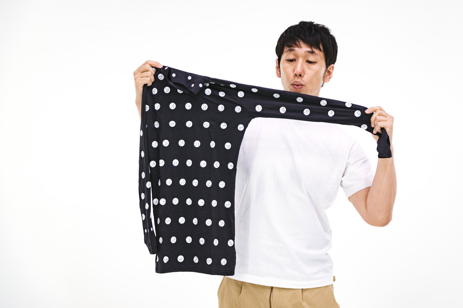 黒地に白いドット柄の採寸ボディースーツを両手で広げて伸縮性を確認する男性［モデル：大川竜弥］