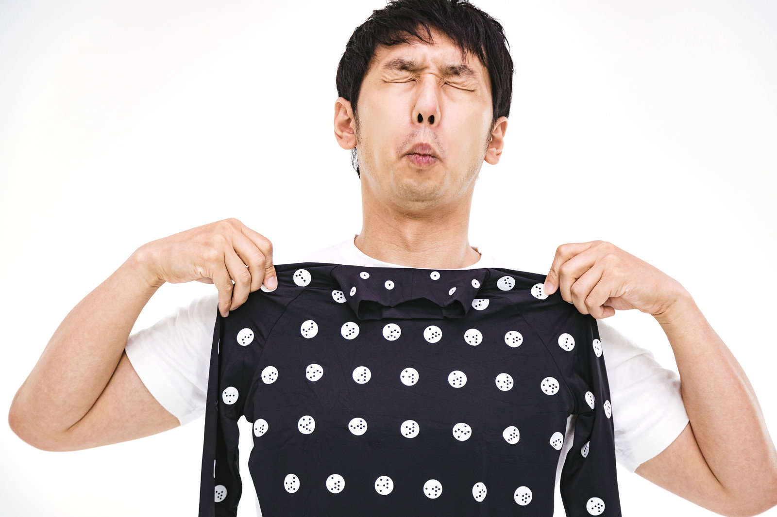黒いドット柄の採寸ボディースーツを両手で持つ困った表情の男性［モデル：大川竜弥］