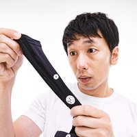 採寸ボディースーツZOZOSUITの伸縮性に驚く男性の写真