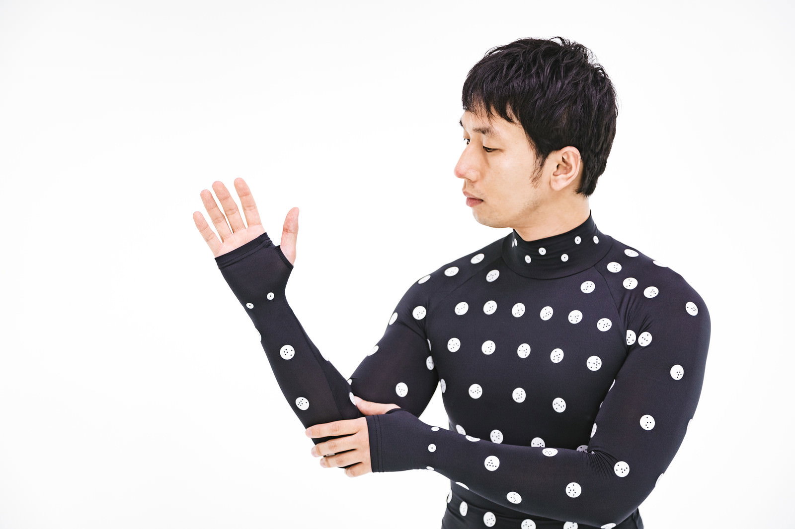 黒いドット柄の採寸ボディースーツを着用し手を上げる男性［モデル：大川竜弥］