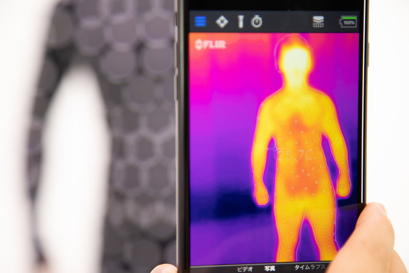 スマートフォンの画面にサーモグラフィーで撮影された人の体温画像が表示されている
