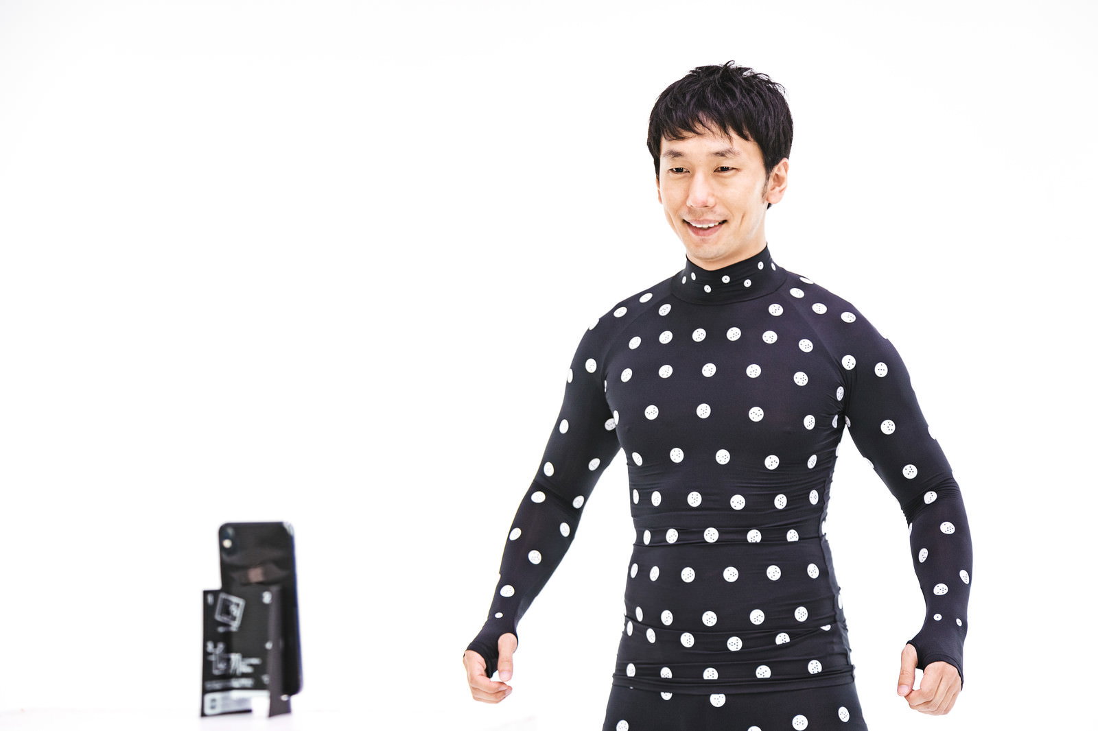 黒いドット柄のZOZOSUITを着用し、両腕を軽く広げて採寸ポーズをとる男性［モデル：大川竜弥］