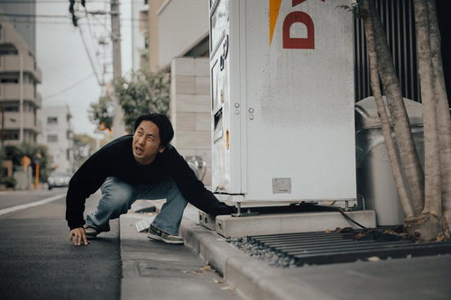 自販機の釣り銭口で小銭を拾う男性