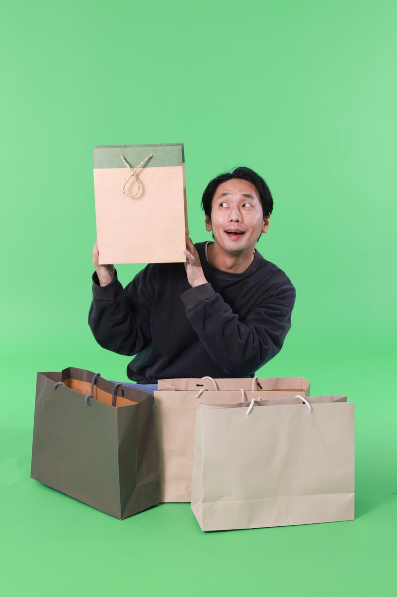 ブラックフライデーの配送品に喜ぶ男性とショッピングバッグ［モデル：大川竜弥］