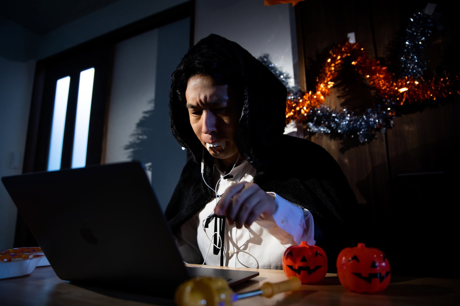 ハロウィンのドラキュラコスプレをしてパソコン作業をする男性エンジニア［モデル：大川竜弥］