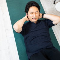 自宅のヨガマットで腹筋する男性の写真