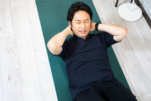 自宅のヨガマットで腹筋運動する男性のトレーニング風景