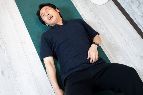 運動不足で力尽きて横になる男性のトレーニング風景