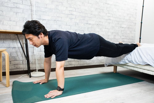 自宅のベッドでできるトレーニング。腕立て伏せで筋トレする男性