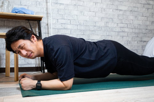 険しい表情でプランクを続ける男性の体幹トレーニング