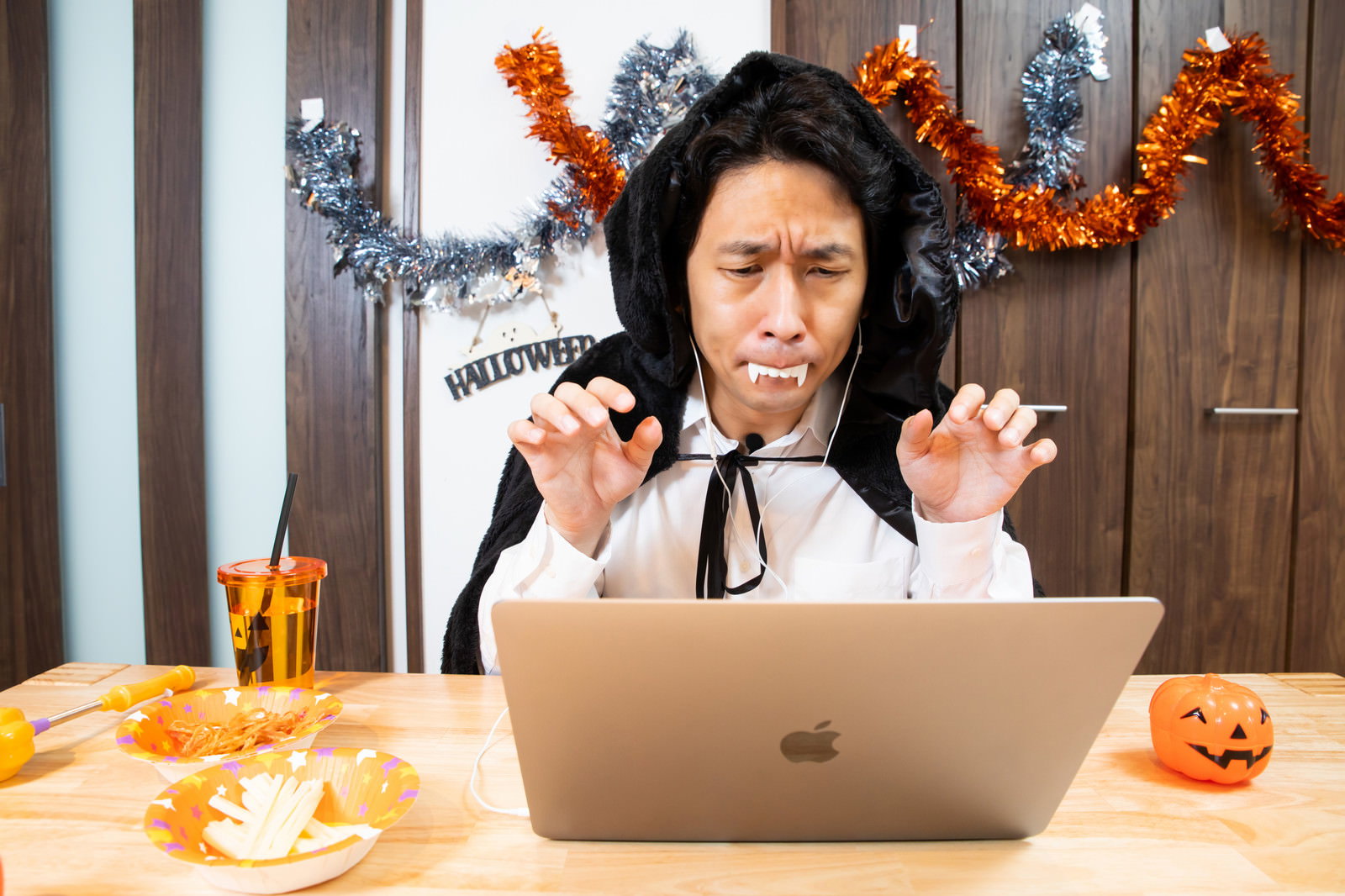 悪魔の角を付けてノートパソコンでオンライン通話するハロウィン仮装の男性［モデル：大川竜弥］