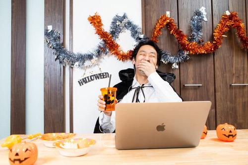 ハロウィンの仮装でノートパソコンを使ってリモート飲み会に参加する男性