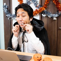 張り切ってハロウィンのリモート飲み会の準備をする男性の写真