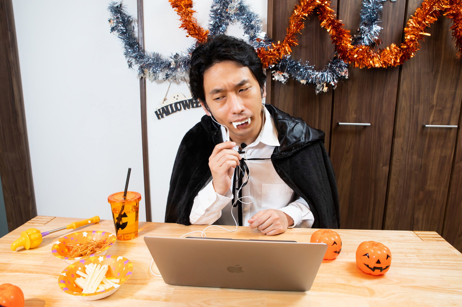 ドラキュラの仮装をしてノートパソコンでリモート飲み会をする男性
