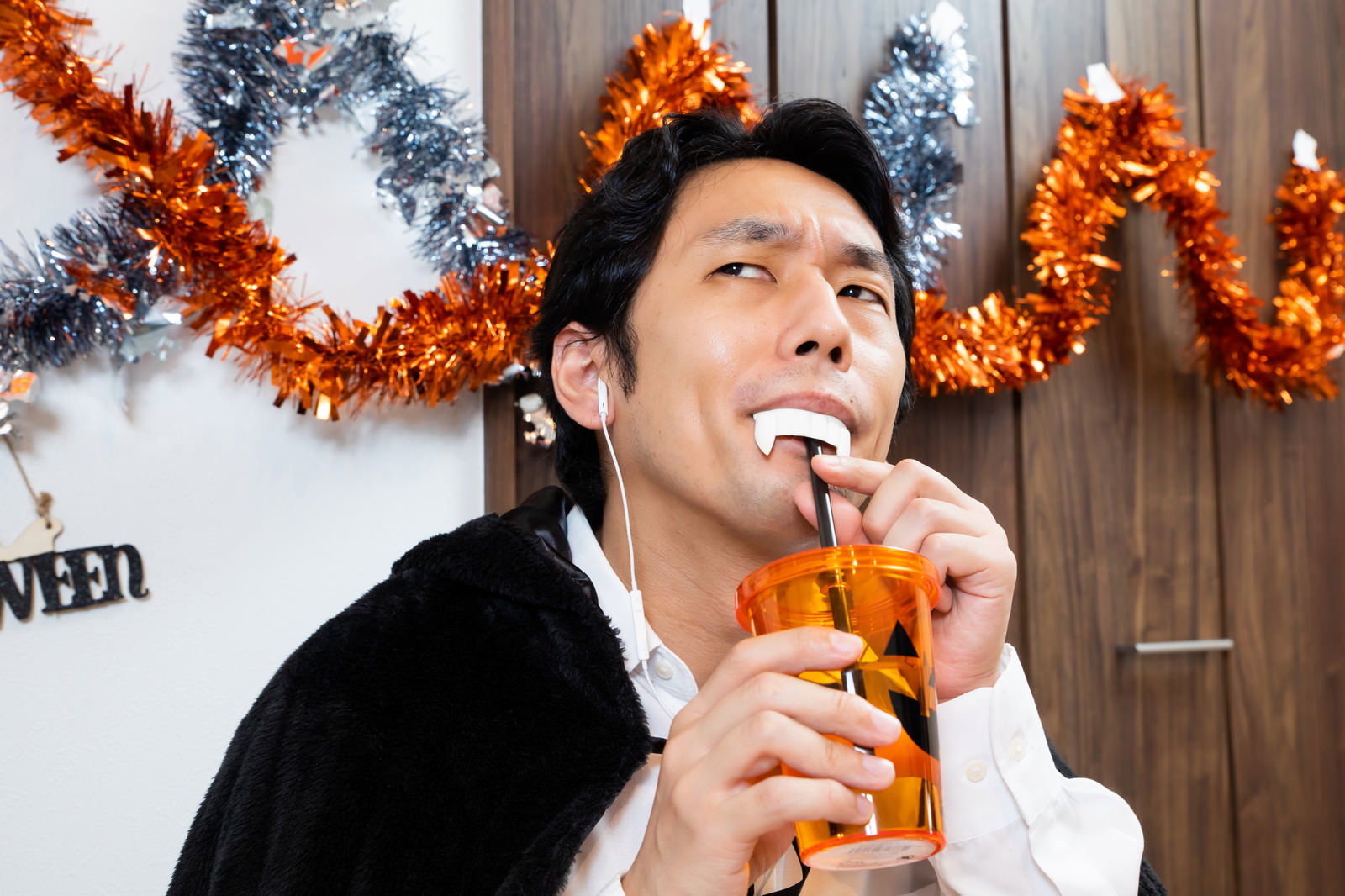 ドラキュラの仮装をしてオレンジジュースを飲む男性［モデル：大川竜弥］