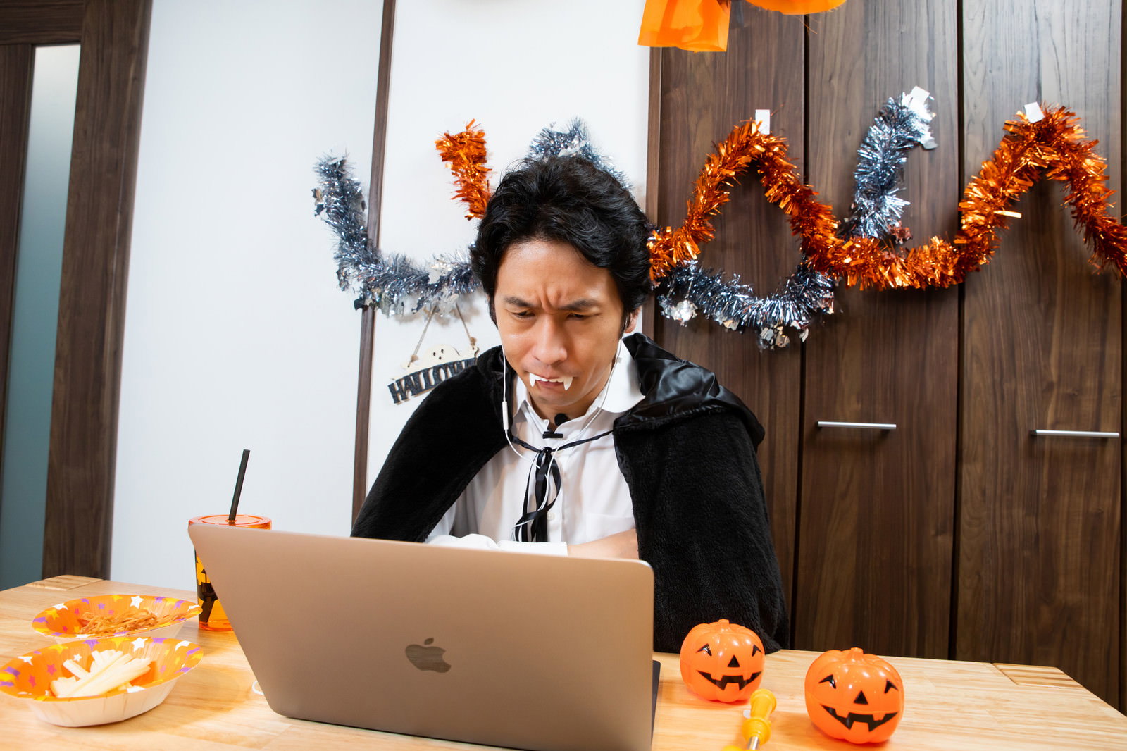 ハロウィンの仮装をしてパソコンでリモートワークをする男性［モデル：大川竜弥］