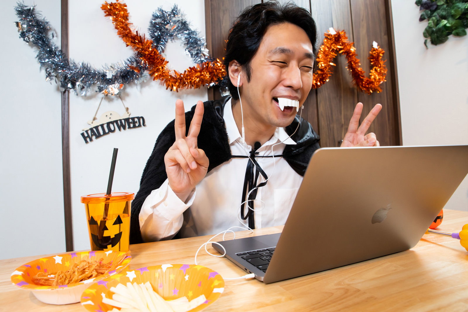 ハロウィンのドラキュラコスプレでオンライン飲み会を楽しむ笑顔の男性［モデル：大川竜弥］