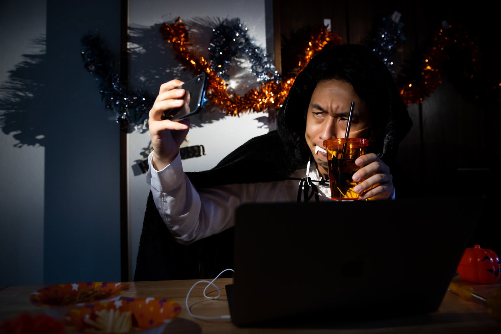 ハロウィンのドラキュラ仮装をしてノートパソコンで配信する男性
