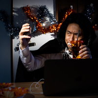 ハロウィンのドラキュラ仮装でノートパソコンの生配信をはじめる男性の写真