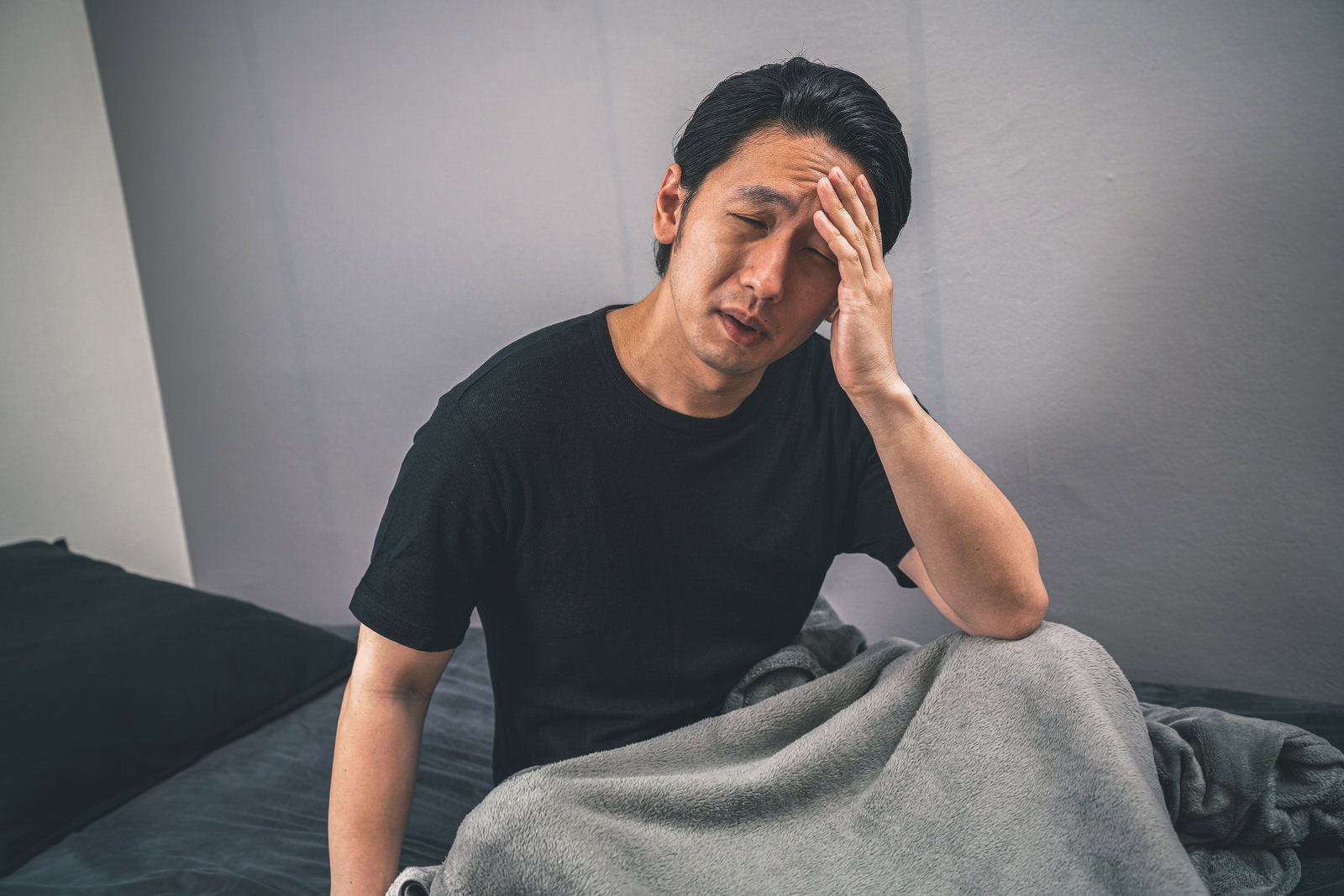 頭を抱えて体調不良を訴える黒いTシャツの男性