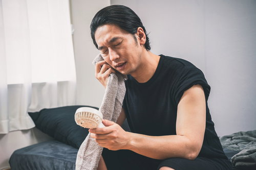 ハンディ扇風機で涼む黒いTシャツの男性の熱中症対策