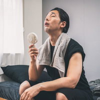 携帯扇風機の風で暑さをやり過ごす男性の熱中症対策の写真