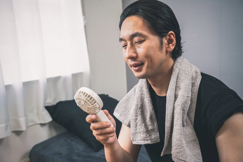 風呂上がりにハンディ扇風機で涼む男性