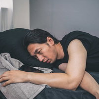 熱中症でぐったりしてベッドに横たわる男性の写真