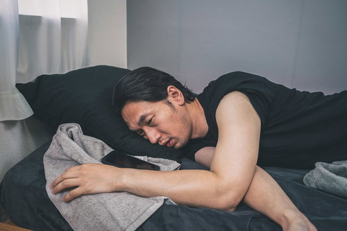 熱中症でぐったりしてベッドに横たわる男性