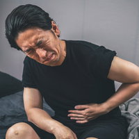 冷房病による腹痛で苦しむ男性のベッドでの症状の写真