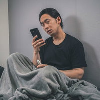 発熱外来を調べる体調不良の男性が体温計で検温の写真