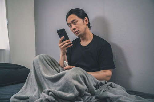 発熱外来を調べる体調不良の男性が体温計で検温