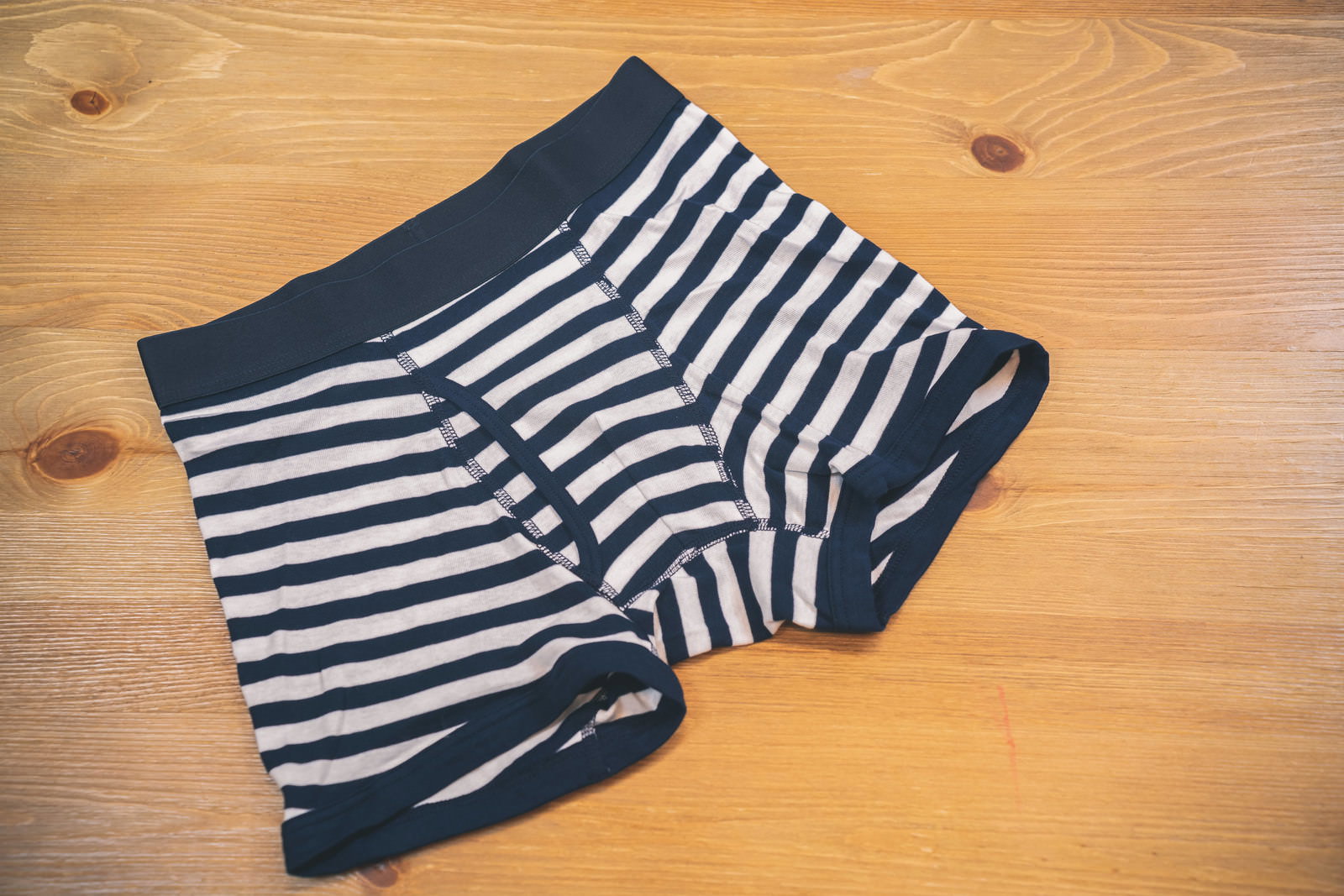 木製テーブルの上に置かれたネイビーとホワイトのストライプ柄の新品ボクサーブリーフ