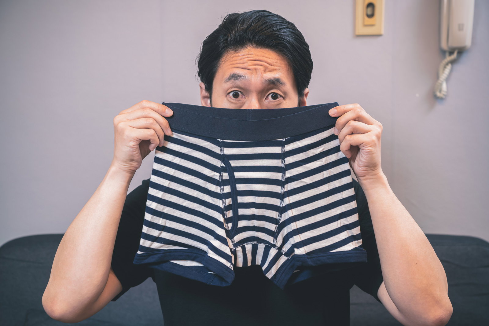黒白ボーダー柄のボクサーブリーフを顔に近づけにおいを嗅ぐ男性［モデル：大川竜弥］