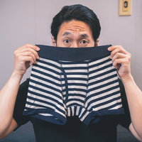 黒白ボーダー柄のボクサーブリーフのにおいを嗅ぐ男性の写真