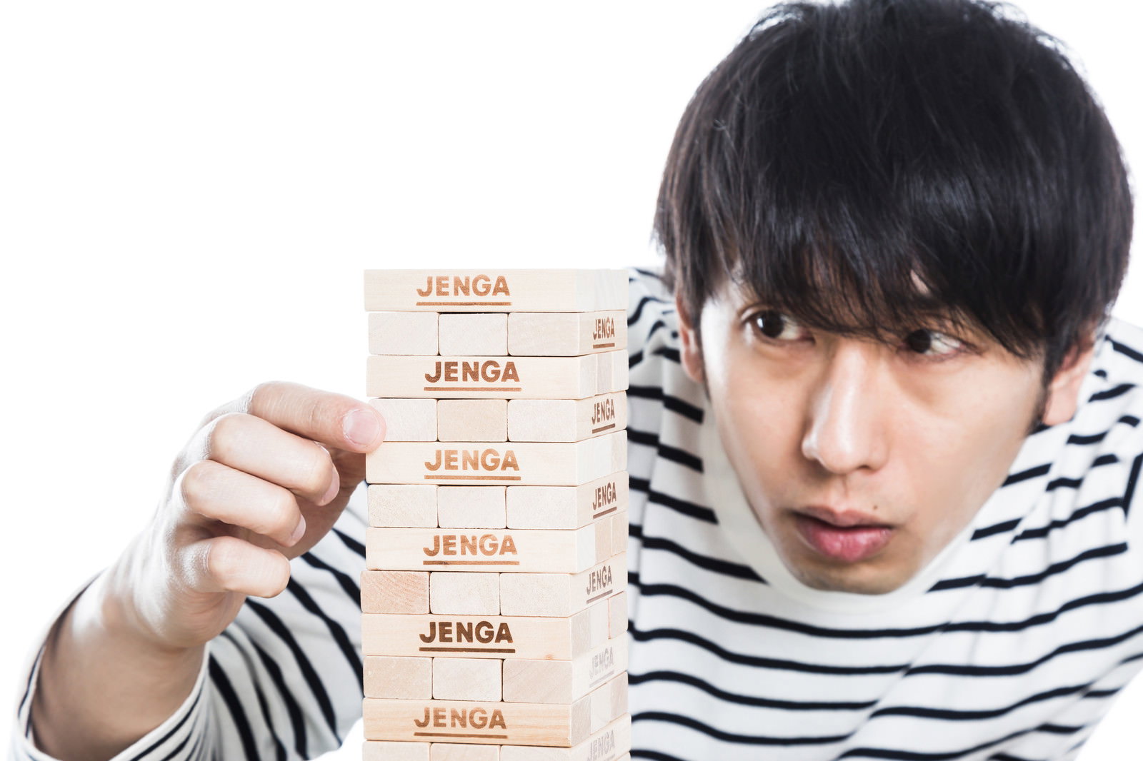 ジェンガのブロックを引き抜く男性［モデル：大川竜弥］