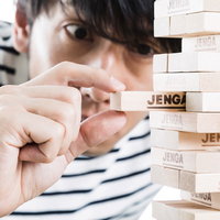 ジェンガで緊張の一瞬、木製ブロックを引き抜く男性の手の写真