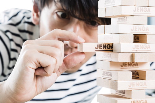 ジェンガで緊張の一瞬、木製ブロックを引き抜く男性の手