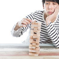 寂しく一人でジェンガで時間つぶしをする男性の写真