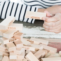 崩れたジェンガのブロックを握る子どもの手の写真