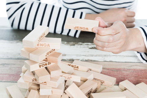 崩れたジェンガのブロックを握る子どもの手