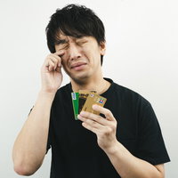 クレジットカードを持ちながら涙を流すクレカ男子の写真