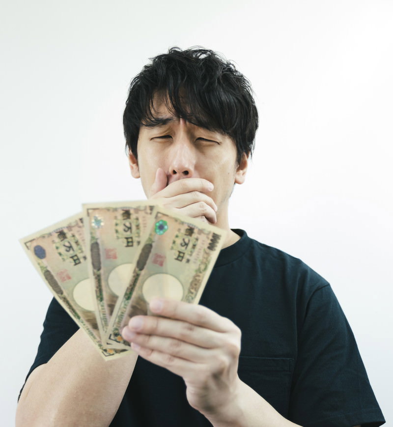 一万円札を手に持って嬉しそうな表情を浮かべる黒髪の男性