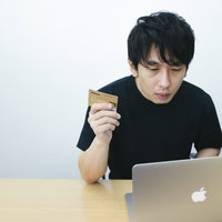 ノートパソコンでネット上の買い物をクレカ決済する男性の写真