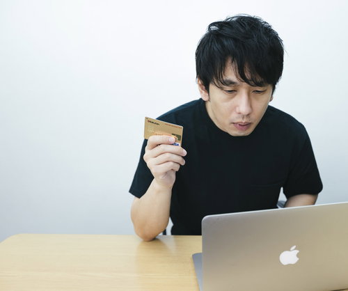 ノートパソコンでネット上の買い物をクレカ決済する男性