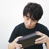 空になった財布を見つめる生活苦の男性の写真