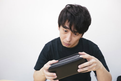 空になった財布を見つめる生活苦の男性