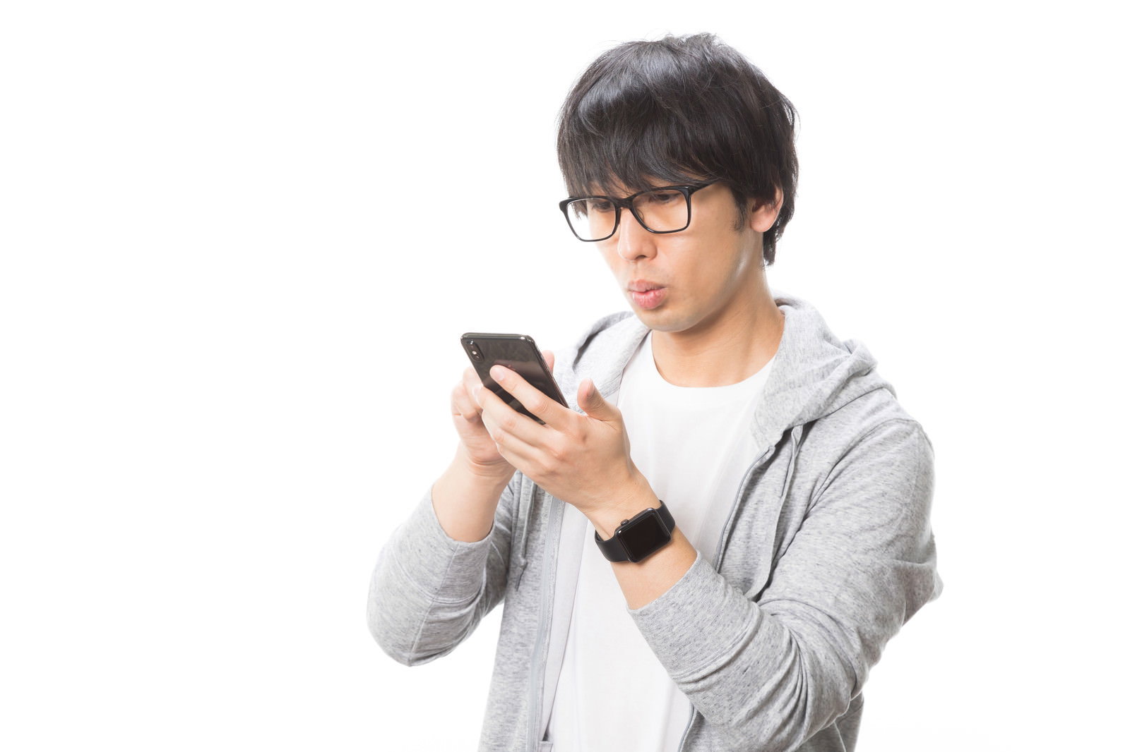グレーのパーカーを着た眼鏡の男性がスマートフォンを操作している［モデル：大川竜弥］