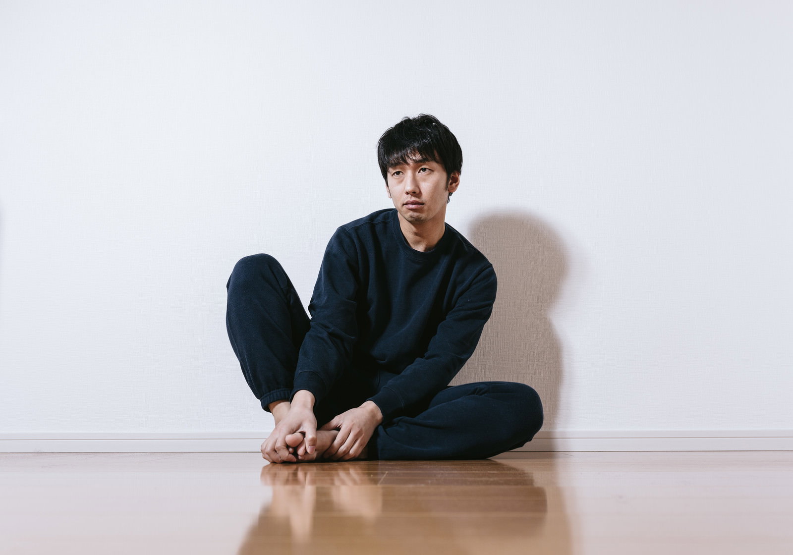 床に座って時計を見つめる男性
